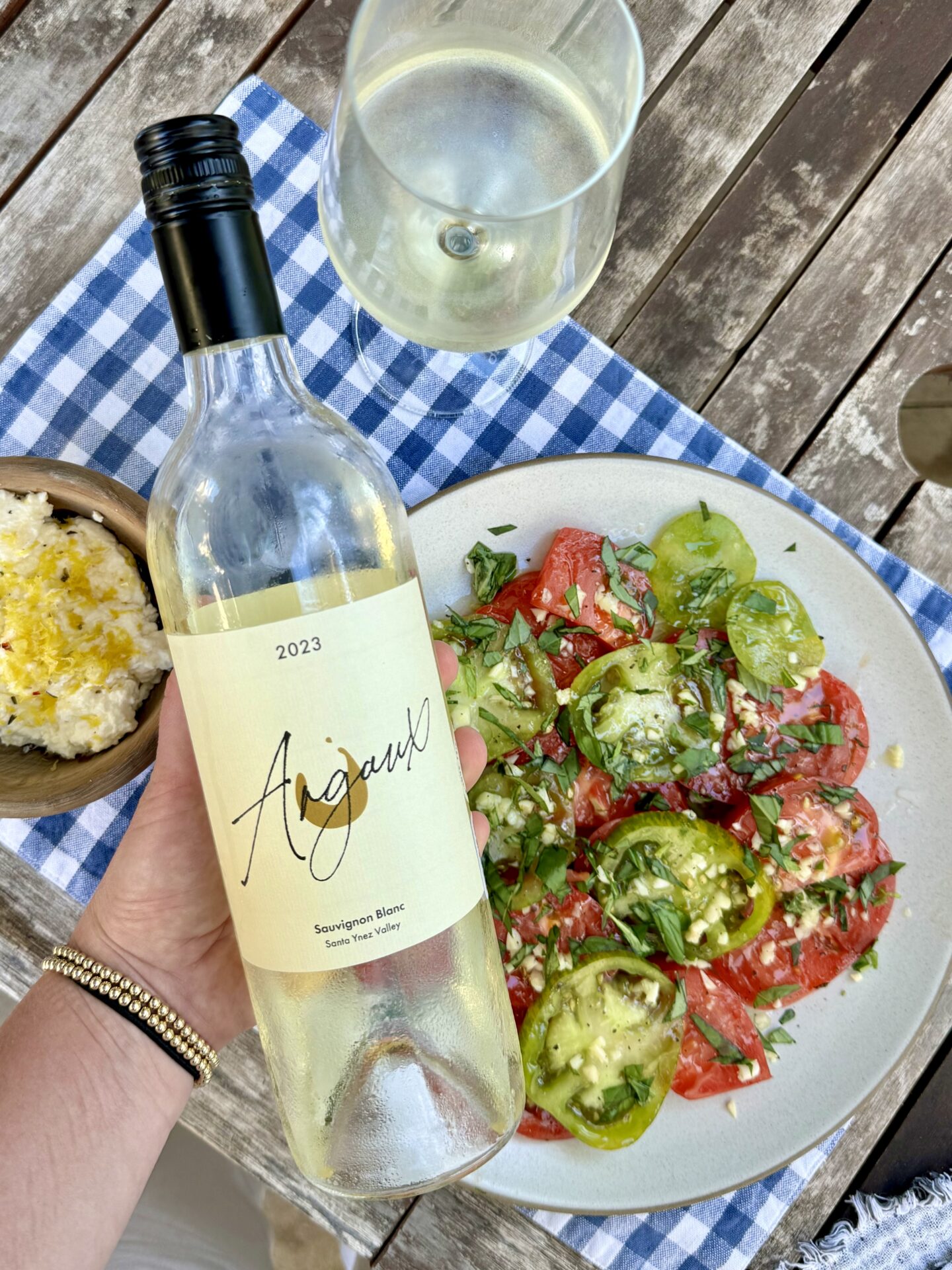 Bottle of Argaux Sauvignon Blanc on picnic table with fresh tomatoes on a plate.