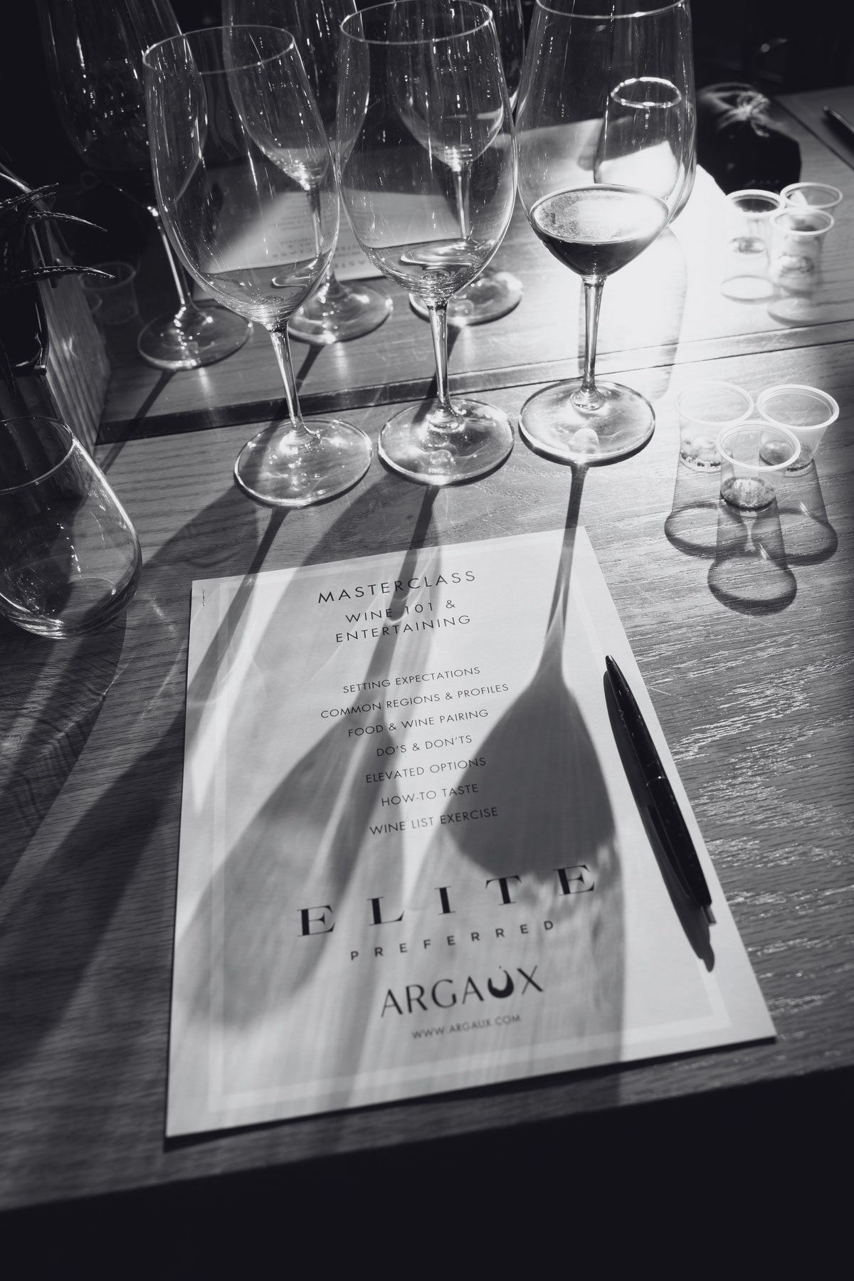 Wine glasses on a table with an 'Elite' Argaux menu in the foreground
