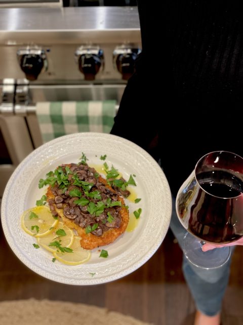 Photo of Chicken Marsala on a plate with red wine. 
