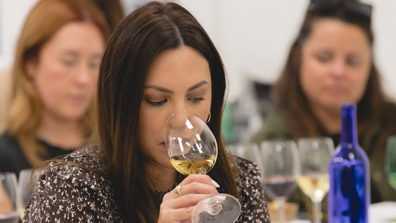 Woman smelling wine at a wine tasting event with blurred background